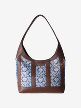Brown leather handbag with blue/white floral jacquard on a white background