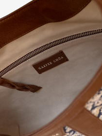 Close-up of a beige twill interior lining with a silver-tone CASPER CHOA stamped signature on brown calfskin and a silver zipper with brown calfskin zipper pull